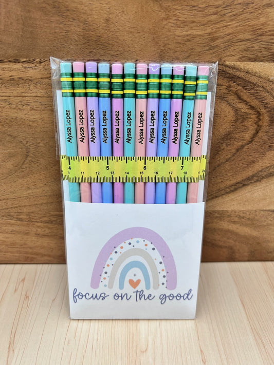 Pack of colorful pencils with a ruler on a wooden surface, featuring a motivational quote.