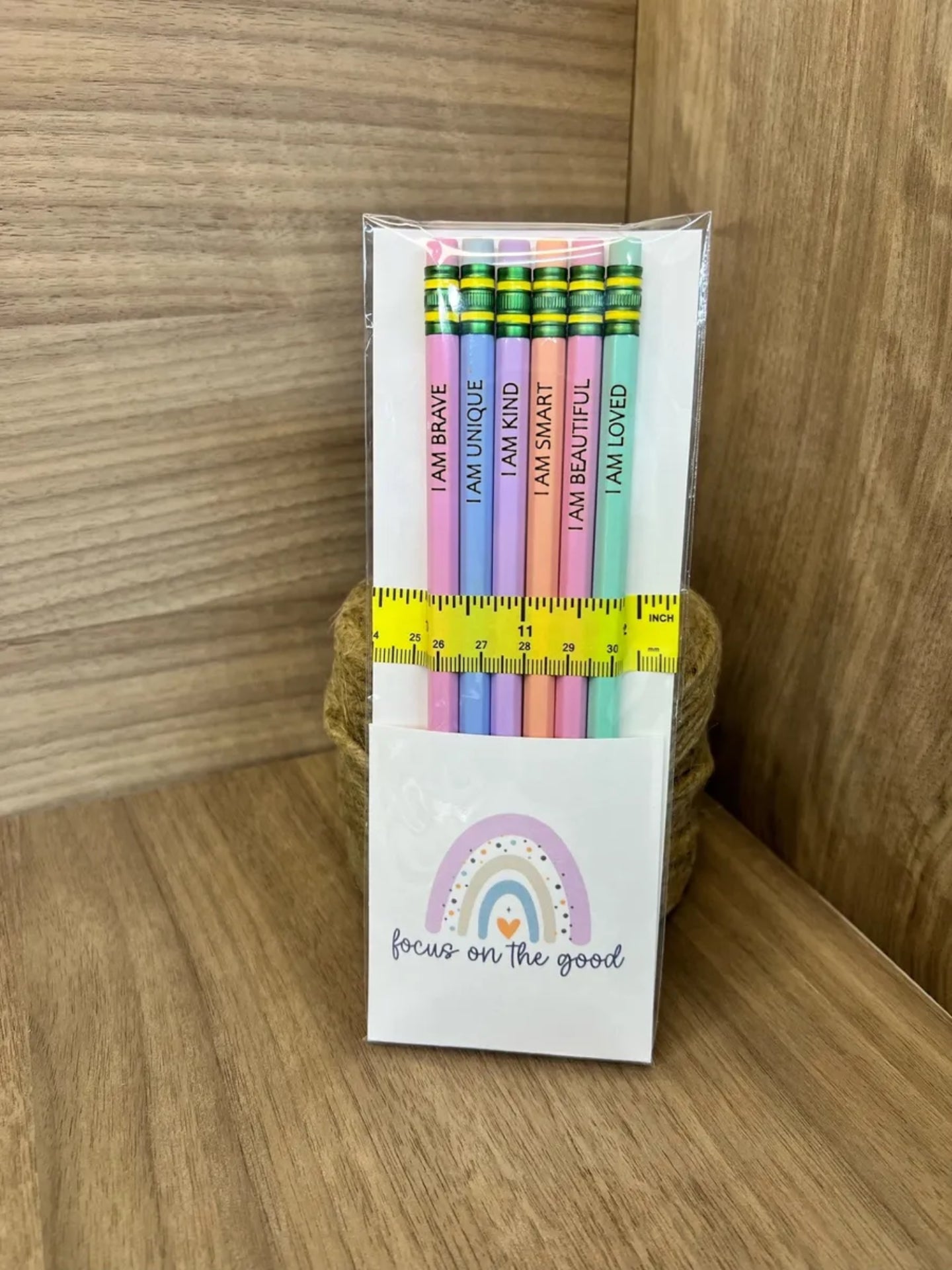 Pack of colorful pencils with motivational phrases in a white box on a wooden surface.