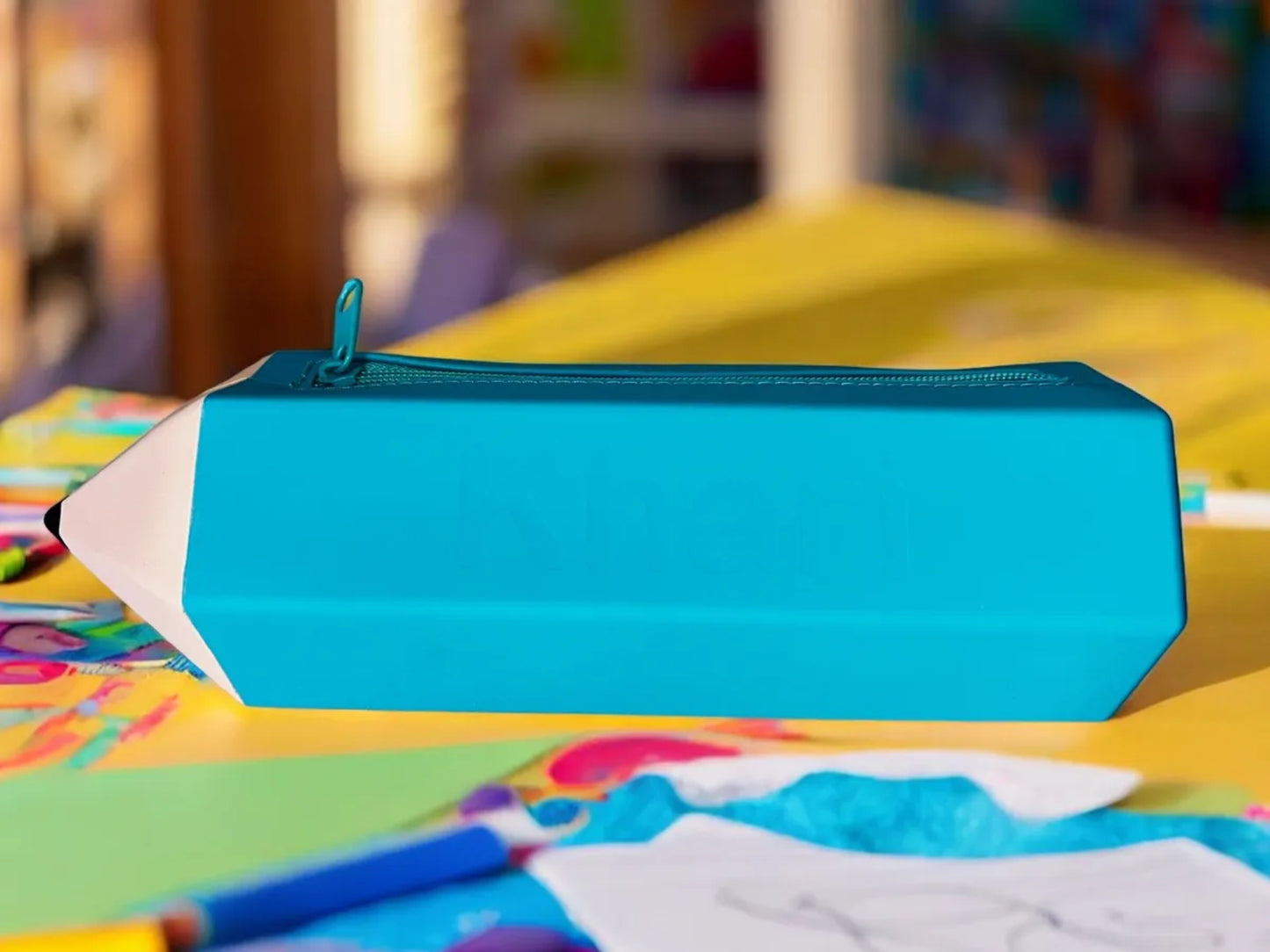Blue pencil-shaped case on a colorful surface with a blurred background