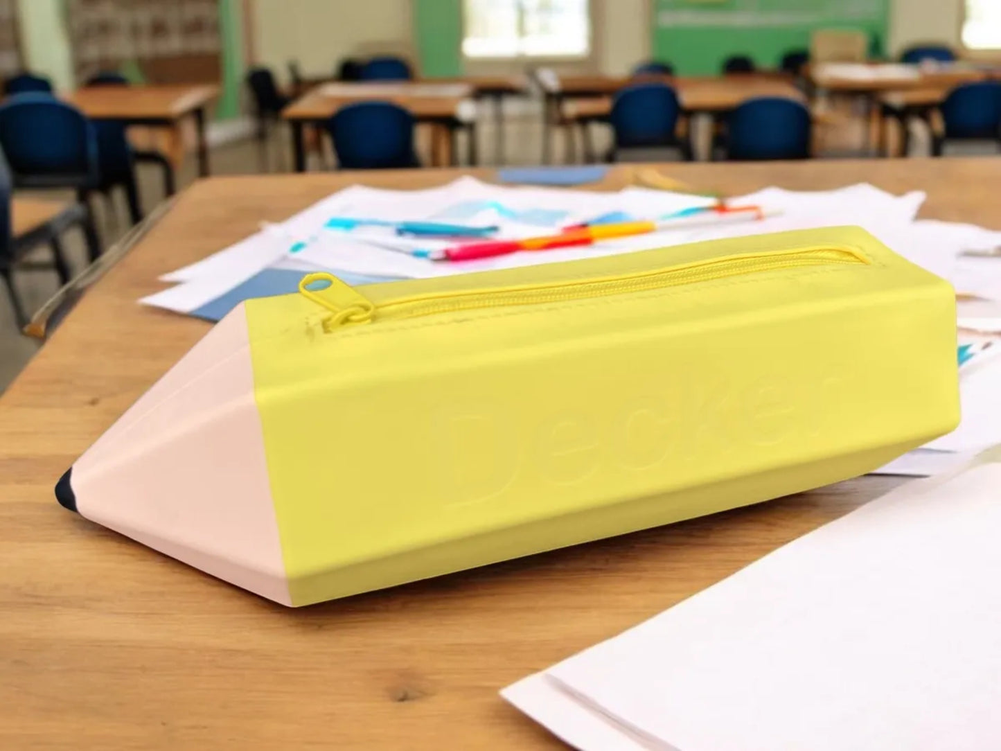 Yellow engraved pencil case on a desk with classroom setting in the background