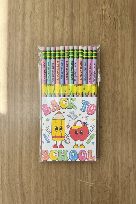 Pack of colored pencils with a 'Back to School' themed card on a wooden surface