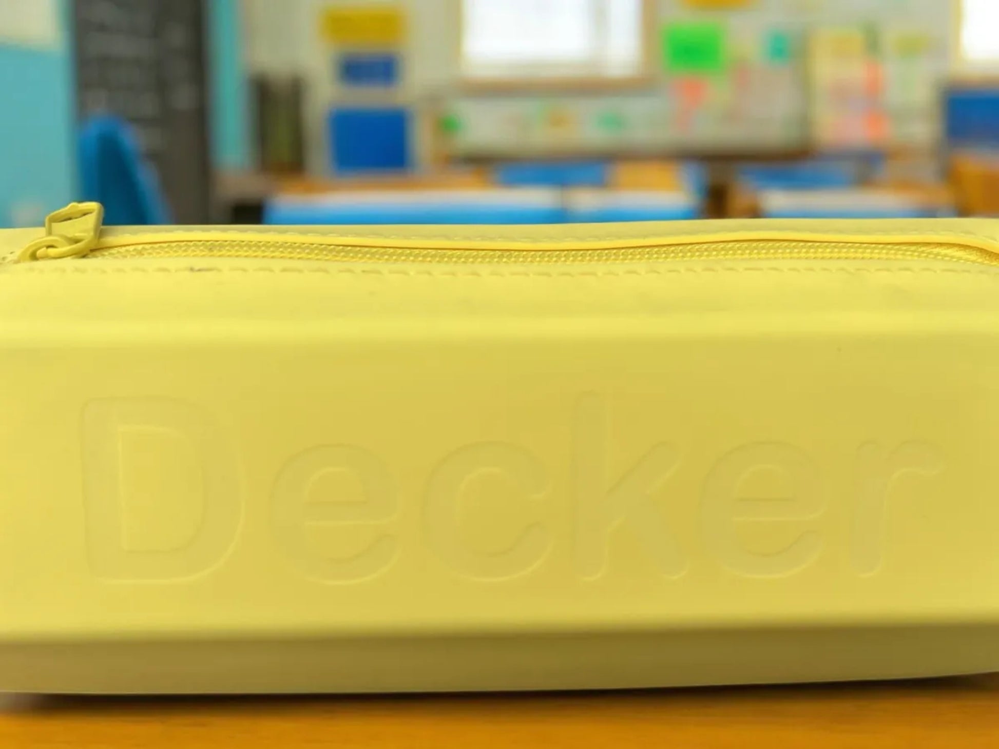 Yellow case with 'Decker' branding on a blurred classroom background