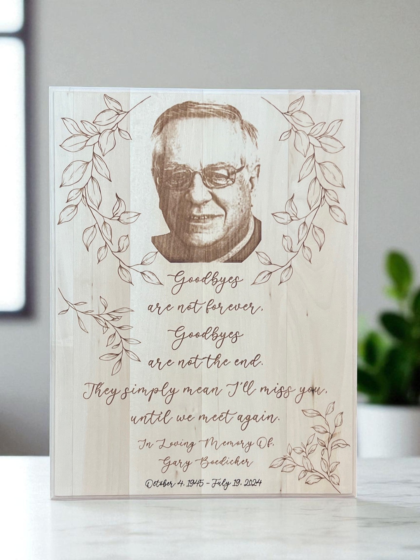 Memorial card with a portrait of a man and engraved text on a wooden surface.